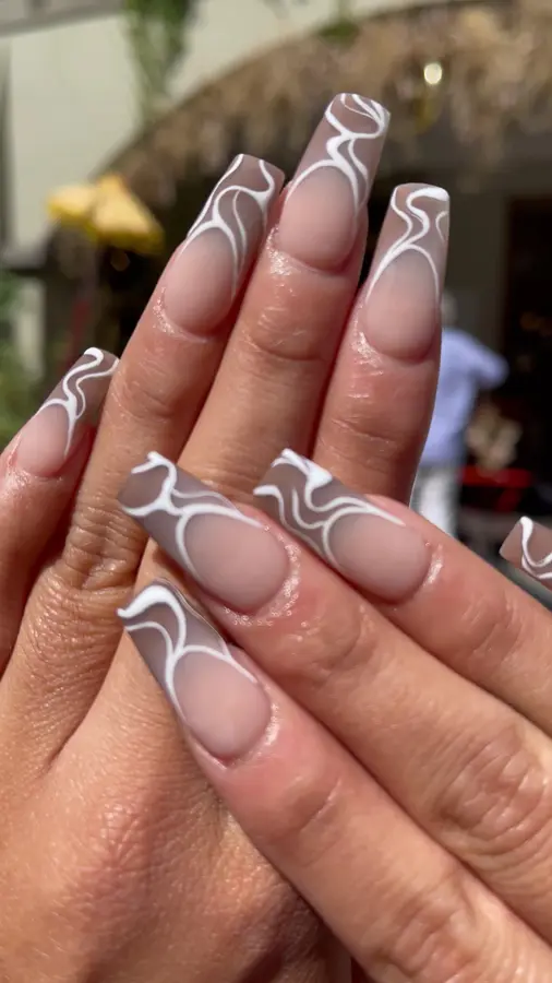 Lange, eckige Nägel in Nude mit weissen und braunen Swirls